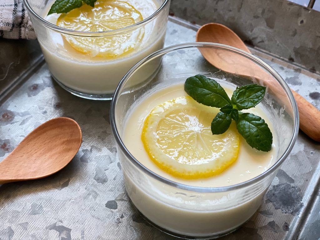 グラスに盛られたレモンポセット。上にはちみつ漬けの薄切りレモンとミントが飾られた、華やかなおもてなしデザート。