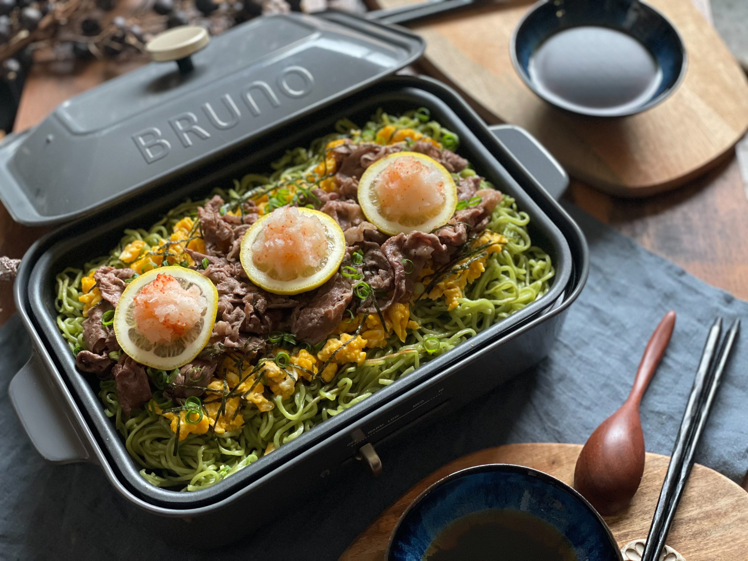 山口県の郷土料理をおうちで再現！ホットプレートで仕上げる「我が家の瓦そば」。茶そばの緑とトッピングの黄色・赤が鮮やかな、パーティーにもぴったりの写真。